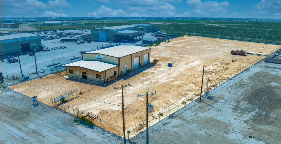 Aerial view of a fenced industrial yard with a shop and office building at 1500 S County Road 1309, Midland, Texas